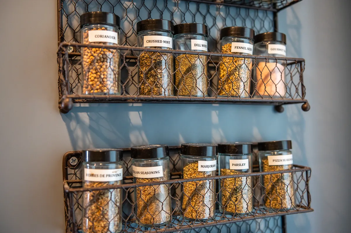 Organized spice jars on a wire rack, each clearly labeled, evoke both order and culinary adventure. The focus is on the tools and small details that make cooking enjoyable and efficient.