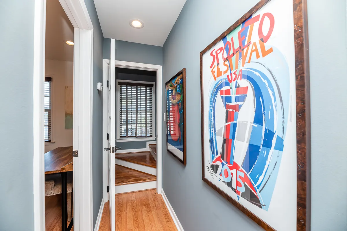 This interior image highlights a staircase bathed in natural light, accompanied by colorful artwork on the walls. The open, airy feel underscores the townhouse-style layout and emphasizes the journey further into the home from the entry.