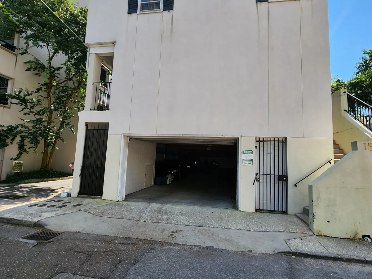 This exterior image displays the parking entrance to the townhouse-style condo, featuring a staircase and lush side vegetation. The entryway sets the scene for arrival and departure, emphasizing the property's connection to the surrounding urban core.